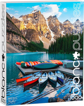 Blanc Puzzles jigsaw puzzle titled 'Lake Moraine' featuring a picturesque landscape of Moraine Lake surrounded by majestic mountains and colorful canoes. The image showcases a calm turquoise lake reflecting the stunning scenery, offering a serene and tranquil vibe perfect for puzzle enthusiasts.