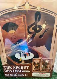 The Secret Rhythm DIY Book Nook Kit by Tonecheer features a decorative design with musical notes and a vintage record player as its centerpiece. Ideal for creating a charming bookshelf accent, the kit includes all necessary components for assembly, highlighting creativity and craftsmanship.