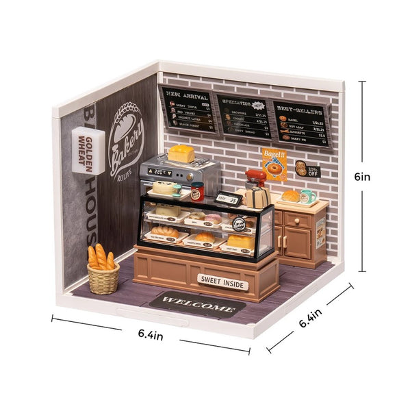 Detailed miniature scene of a bakery called Golden Wheat. Features include a display case with various baked goods, an oven on the side, a basket of bread, and a signboard with menu items. Dimensions are approximately 6.4 inches in length and width, and 6 inches in height.