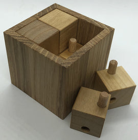 Akaho XS Mechanical Puzzle by VINCO, featuring a wooden block structure with various smaller pieces that fit inside. The main block has a natural wood finish, emphasizing its craftsmanship and providing an intriguing challenge for puzzle enthusiasts.