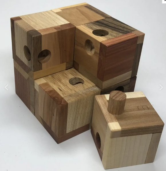 Akadia M Mechanical Puzzle by VINCO features a unique assembly of wooden blocks in various natural shades. Each block has holes and pegs, inviting users to solve through manipulation and creativity. Ideal for enhancing cognitive skills and providing an engaging hands-on challenge.