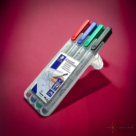 A transparent case containing four water soluble markers by Chessex, featuring red, blue, green, and black colors. Each marker is labeled and designed for easy grip, suitable for various art projects and games.
