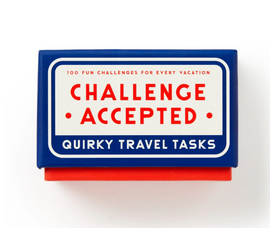 Challenge Accepted Travel Task game box featuring a vibrant blue design with bold red and white lettering. The box promises 100 fun challenges for every vacation, making it a perfect companion for adventurers and travelers looking to add excitement to their journeys.