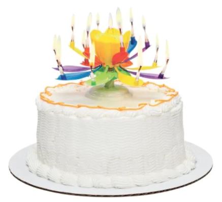 A festive white birthday cake adorned with colorful frosting and a vibrant flower-shaped candle holder on top, featuring multiple lit candles that create a joyful atmosphere suitable for celebrations.