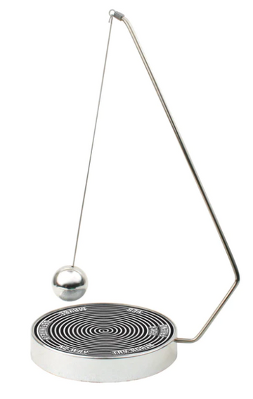The Decision Maker by Kikkerland features a sleek metallic design with a pendulum ball on a springy arm. The base has a spiral pattern and labels indicating options like 'Yes', 'No', and 'Maybe', making it a playful tool for decision-making.