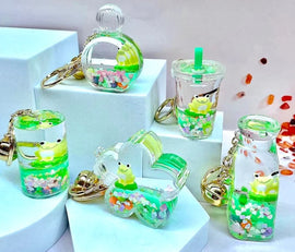 A colorful collection of Frog Boba Floating Keychains in various shapes, including a drink cup, bottle, and heart. Each keychain features a cute frog surrounded by colorful sequins and a transparent body that adds to its charm. The keychains are displayed on a light-colored platform, highlighting their fun and whimsical design, perfect for adding a pop of color to your accessories.