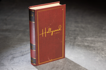 A vintage-style book titled 'Hollywood 1947' by Facade Games, displayed upright. The book features a rich burgundy cover with elegant gold lettering and decorative elements, resembling a classic novel.
