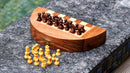 A beautifully crafted 9-inch round wooden chess set by R. Expo. The set features finely detailed chess pieces displayed on a striped chessboard. The board is designed to fold up for easy storage, showcasing a rich wood finish. Several yellow pawn pieces are laid out next to the board, indicating readiness for play.
