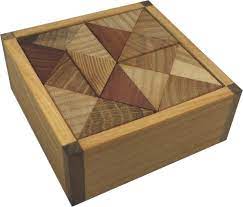 A beautifully crafted mechanical puzzle named Cuboid by VINCO. The puzzle consists of interlocking wooden pieces featuring a geometric design in various shades of brown and tan, all housed in a wooden frame that adds to its aesthetic appeal. Perfect for puzzle enthusiasts and those seeking a challenge, this item combines artistry with engaging gameplay.