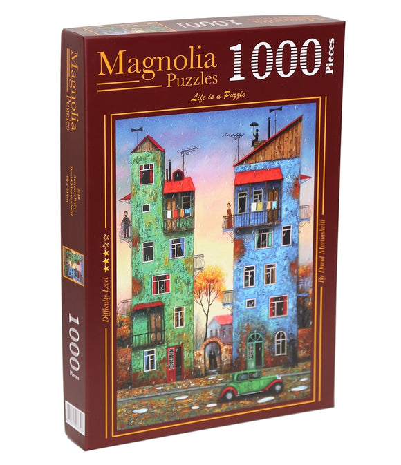 A jigsaw puzzle box titled 'AUTUMN RAIN' by Magnolia Puzzles. The box features a colorful illustration of vibrant buildings with trees in autumn tones, designed by Daniel Mondzinski. It contains 1000 pieces, marked with a difficulty rating of 'Easy'.