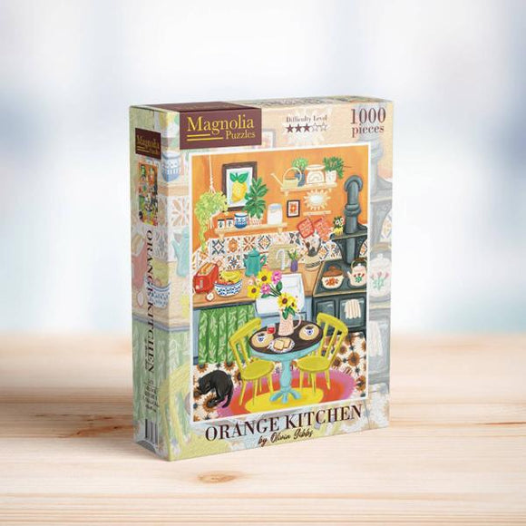 A jigsaw puzzle box titled 'ORANGE KITCHEN' by Magnolia Puzzles featuring a colorful illustration of a cozy kitchen scene with green chairs, kitchenware, and a cat. The box contains 1000 pieces and is noted for its challenging difficulty level.
