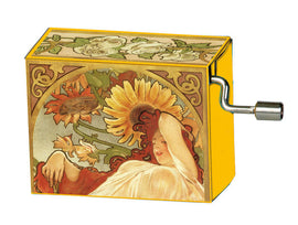 A decorative music box titled 'Summer 1879' by Fridolin. The box features vintage artwork of a woman lounging amidst sunflowers and roses, exuding a nostalgic charm. The crank mechanism is visible on the side.