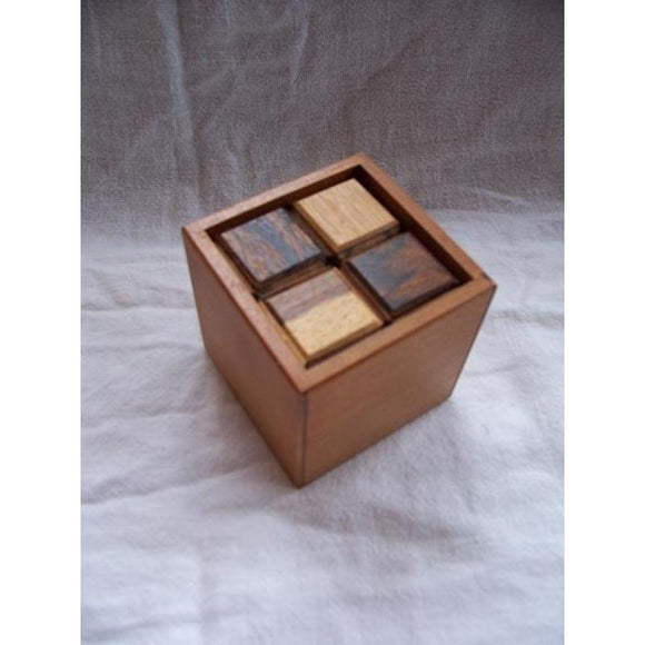 This is a wooden mechanical puzzle called Pieces-of-Eight-Coffin by Eric Fuller. The puzzle features a cubic box design with four distinct wooden pieces on top, each varying in color and texture. Ideal for puzzle enthusiasts and collectors, the craftsmanship showcases fine attention to detail, making it both a beautiful display item and a mentally engaging challenge.