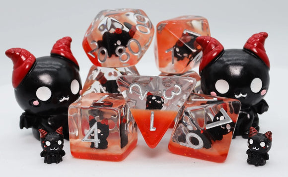Colorful Baby Fiend RPG Dice Set featuring black and red themed dice with cute devilish designs. The set includes various types of polyhedral dice, perfect for tabletop gaming enthusiasts. The dice are surrounded by adorable mini figures, enhancing the playful aesthetic of the set.