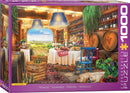 A colorful jigsaw puzzle box featuring a picturesque winery scene with tables set for a feast, bottles of wine lining the walls, and scenic vineyards outside. Two golden retriever puppies are resting on the floor, adding a cozy touch to the vibrant atmosphere filled with lights and greenery.