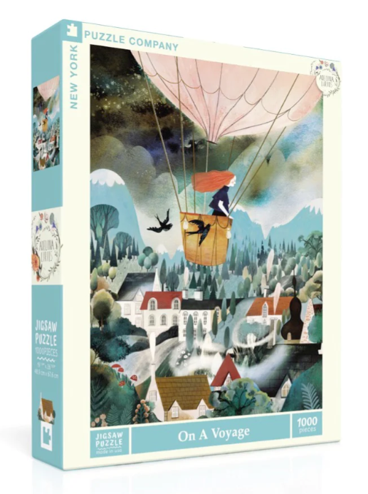 The On a Voyage jigsaw puzzle by New York Puzzle Company features a whimsical illustration of a hot air balloon soaring over a picturesque landscape. The colorful artwork displays a woman in the basket with flowing red hair, accompanied by birds, as it glides above charming houses and lush greenery, inviting puzzlers into a serene adventure.