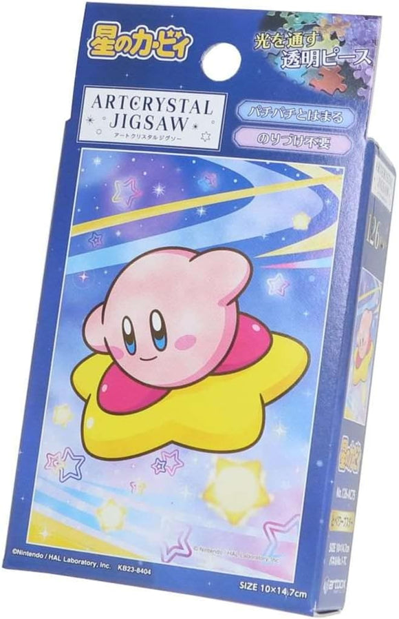 The box for the Fly Warp Star Kirby Petite Cry jigsaw puzzle by Ensky features a colorful illustration of Kirby, a pink, round character, sitting on a yellow star against a night sky background filled with stars and swirls of blue and purple. The packaging is vibrant and designed to attract fans of Kirby and puzzle enthusiasts alike.