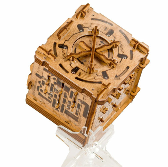 Cluebox - Cambridge Labyrinth is a mechanical puzzle made from intricately designed wood. It features a cube shape with elaborate carvings and moving parts that create a labyrinth challenge. The puzzle is displayed on a clear stand, showcasing its detailed craftsmanship and complex mechanisms.
