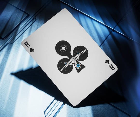 A close-up image of a Star Trek-themed playing card featuring a unique design with a representation of a spaceship and celestial elements. The card is shown on a reflective blue surface, enhancing its futuristic aesthetic. The card belongs to the suit of clubs, showcasing a creative blend of science fiction and traditional card game elements, perfect for Star Trek fans and card game enthusiasts alike.