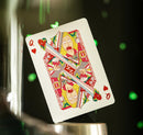 A close-up of a Rick & Morty themed playing card, featuring a colorful illustration of a character with exaggerated expressions. The card displays the Queen of Hearts with a vibrant design that includes elements of humor and excitement, perfect for fans of the show. The background features a blurred, sparkling green element that adds an engaging atmosphere.