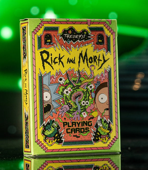 A vibrant and colorful design of Rick & Morty Playing Cards by Theory 11, showcasing dynamic artwork featuring Rick and Morty surrounded by animated, quirky elements. The box is primarily yellow with intricate patterns and character illustrations, reflecting the show's adventurous and humorous essence. The cards are perfect for fans and gamers alike.