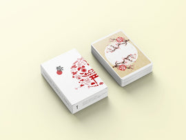 A deck of Matsuri playing cards featuring a beautifully designed white box with red and black graphics, including a traditional Japanese character. The cards are displayed fan-out showing intricate designs featuring flowers and traditional motifs in soft colors.