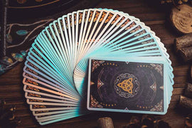 A beautifully arranged set of Magic Crystal Playing Cards by King Star, showcasing an intricate design with shimmering edges. The deck features a unique pattern on the back, blending dark and light elements. The cards are displayed fanned out on a wooden surface, highlighting their glossy finish and vibrant colors.