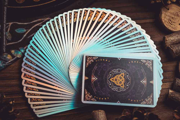 A beautifully arranged set of Magic Crystal Playing Cards by King Star, showcasing an intricate design with shimmering edges. The deck features a unique pattern on the back, blending dark and light elements. The cards are displayed fanned out on a wooden surface, highlighting their glossy finish and vibrant colors.