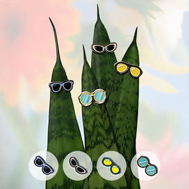 A whimsical display of the Plant Magnet 4 Sunglasses by Eufolia, featuring sunglasses on vibrant green leaf illustrations. The image shows four pairs of sunglasses perched on the tips of slender leaves, accompanied by three additional pairs of sunglasses in a circular arrangement at the bottom of the image, showcasing various colors and styles.
