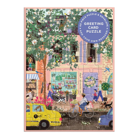 Colorful Spring Street scene featuring a charming cafe, vibrant flowers, and people enjoying the day. This 60-piece jigsaw puzzle includes an envelope for adding a personal message, making it a unique greeting card puzzle.