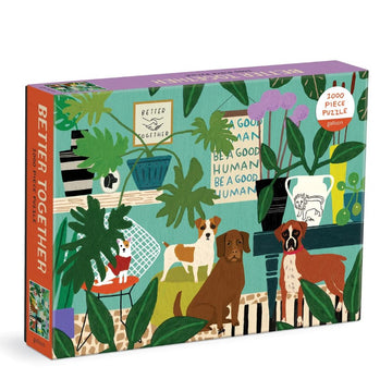 The packaging for the 'Better Together' jigsaw puzzle by Galison features a vibrant illustration of two dogs and a cat surrounded by lush green plants and decorative items. The design includes playful messages such as 'Be a Good Human.' This 1000-piece puzzle is perfect for pet lovers and puzzle enthusiasts.