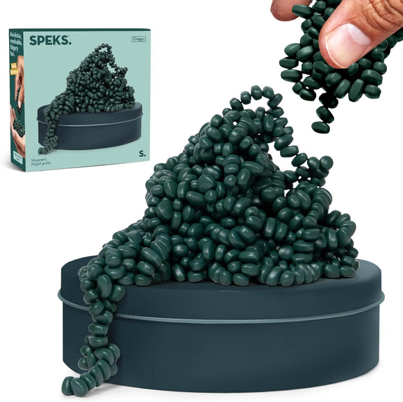 A hand is pouring green jelly-like magnetic fidget putty from above into a round dark green container. The putty is shaped like a mound, illustrating its malleability and fidget-friendly nature. The packaging of SPEKS Crags Matte: Jade is visible in the background, featuring a design highlighting its playful, tactile attributes.
