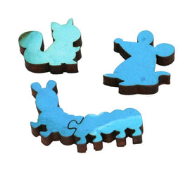 A close-up view of the Mojo Shaped Puzzle pieces by Artifact Wooden Puzzles. Three intricately designed jigsaw puzzle pieces feature colorful animal shapes, including a whimsical squirrel, a playful mouse, and a caterpillar. Each piece is made of high-quality wood, showcasing vibrant blue tones and unique contours, inviting creativity and fun for puzzle enthusiasts.