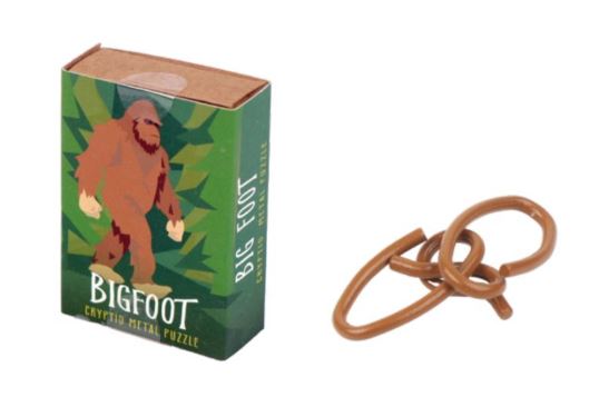 The Cryptid Puzzlebox Bigfoot features a colorful box showcasing a stylized Bigfoot character surrounded by green foliage. Next to the box is a set of intertwined metal rings for the mechanical puzzle, highlighting its complexity and fun.