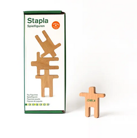 Stapla Balancing Figures made of oakwood displayed next to its packaging. The figures are creatively designed in different poses for imaginative play. The box features a green design with 'Stapla' written on it. Ideal for skill-building and fun activities for children.