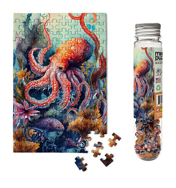 A colorful jigsaw puzzle featuring a beautifully illustrated octopus amidst a vibrant underwater scene with various marine life and plant life. The puzzle pieces are shown around the assembled puzzle, which is displayed next to a transparent container holding the loose pieces.