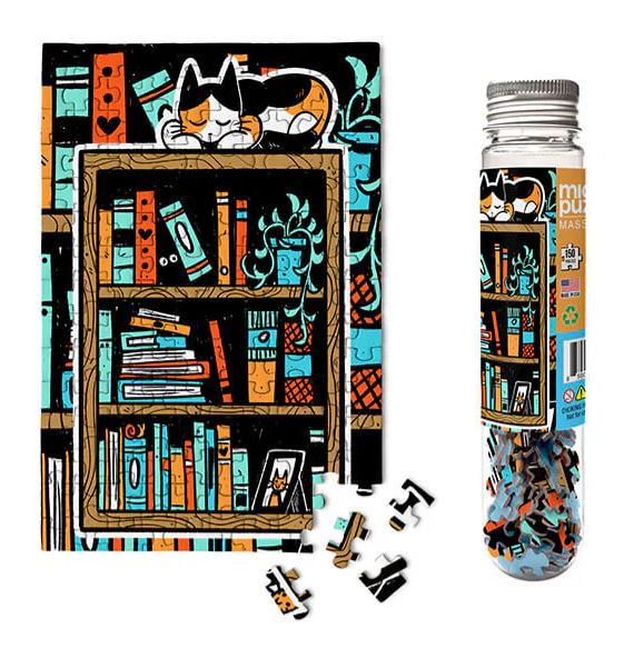 Paws N' Pages Micro Puzzle by Micro Puzzle. This colorful jigsaw puzzle features a playful cat sleeping atop a bookshelf filled with vibrant books, surrounded by plants. The puzzle pieces are displayed in a clear cylinder container, highlighting the intricate design and unique shapes.