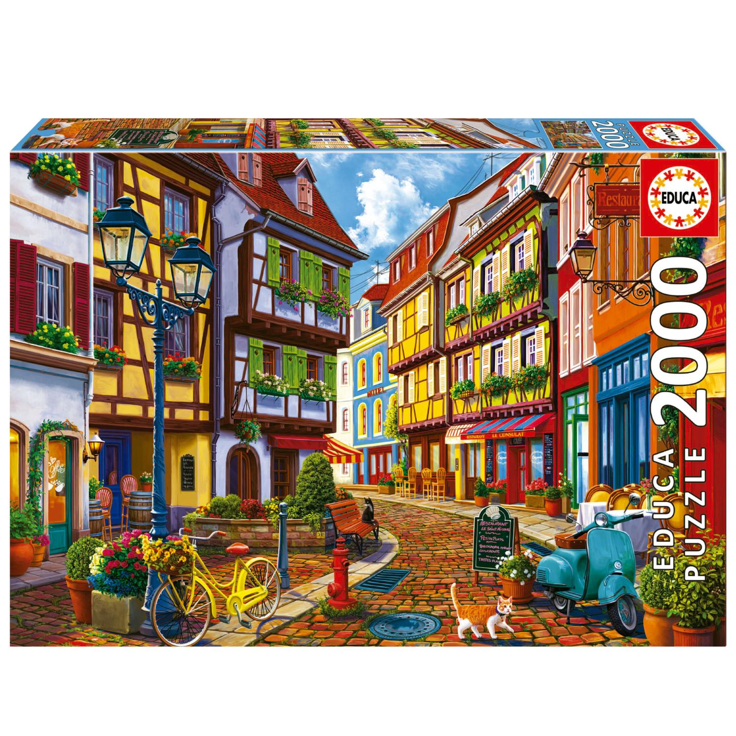 A 2000-piece jigsaw puzzle titled 'Bright Street' by Educa. The vibrant image depicts a charming street scene with colorful buildings, flower pots, a yellow bicycle, and a cat. The artwork features inviting cafes with outdoor seating and lush greenery, capturing the essence of a picturesque town.