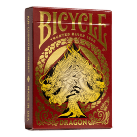 A close-up view of the Bicycle Red Dragon playing cards. The card box features an intricate design with a fierce dragon and gold accents on a rich red background. It showcases the Bicycle logo prominently, highlighting its trusted craftsmanship since 1885, with 'Air-Cushion Finish®' and 'Made in USA' mentioned on the side.