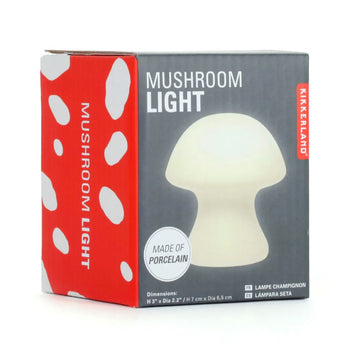 A charming Small Mushroom Light by Kikkerland, shaped like a classic mushroom. The light is made of porcelain and emits a soft glow, perfect for cozy spaces. The packaging features a grey background with the illustration of the mushroom light in white and red accents, stating 'Mushroom Light' and 'Made of Porcelain'.