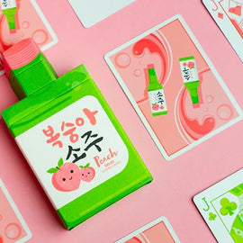 A vibrant set of Peach SOJU playing cards featuring colorful illustrations. The cards display playful peach and SOJU bottle graphics, set against a pink background. Included is a depiction of a bottle of peach-flavored SOJU, highlighted by charming details that celebrate its fruity theme.