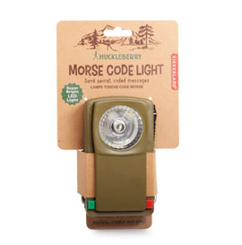 Huckleberry Morse Code Light by Kikkerland, featuring a super bright LED light and an olive green design. The light is compact, making it ideal for sending secret coded messages. Packaging includes instructions for use and promotes exploration and creativity.