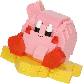 Nanoblock Kirby DIY kit featuring a cute and colorful design of the character sitting on a yellow platform. The Kirby figure is primarily pink with red highlights and white eyes, showcasing its cheerful expression. This block set provides a fun building experience for fans of all ages.