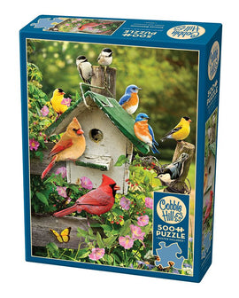 A colorful jigsaw puzzle titled 'Summer Birdhouse' by Cobble Hill, featuring vibrant illustrations of various birds perched on a birdhouse surrounded by flowers, with a total of 500 pieces.