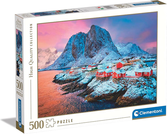 Clementoni 500-piece jigsaw puzzle featuring a stunning winter scene of Hamnøy Village, characterized by colorful houses against a mountainous backdrop, surrounded by water and snow-covered mountains. The puzzle box is displayed showing the vibrant artwork and high-quality collection branding.