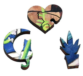 A close-up of three unique wooden jigsaw puzzle pieces featuring vibrant colors and intricate designs. One piece is shaped like a cat sitting, another like a heart with a cat outline, and the third resembling a potted plant. These pieces showcase the artistic details characteristic of the 'Cat In Garden' puzzle by Samuel Haywar.