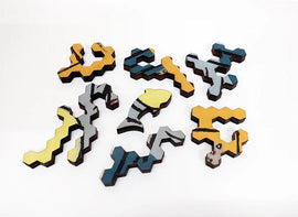 A colorful jigsaw puzzle featuring various uniquely shaped pieces in shades of yellow, blue, and gray, inspired by Picasso's art titled 'The Stranded Fish'. Each piece showcases intricate designs that add to the artistic appeal of the puzzle, making it a wonderful decorative and engaging activity.
