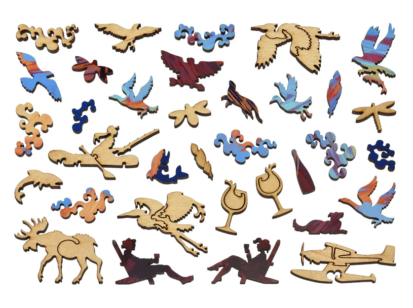 Close-up of whimsical wooden jigsaw puzzle pieces featuring intricate designs including birds, cocktails, and nature themes. The pieces are made from colorful wood, showcasing a variety of shapes and styles. This jigsaw puzzle captures a playful, artistic aesthetic, perfect for puzzle enthusiasts seeking a unique challenge.