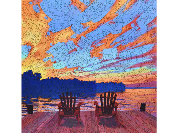 A colorful jigsaw puzzle featuring two red chairs on a wooden dock overlooking a tranquil lake at sunset. The sky is filled with vibrant clouds in shades of orange, pink, and blue, reflecting the peaceful ambiance of the scene. Perfect for puzzle enthusiasts and nature lovers.