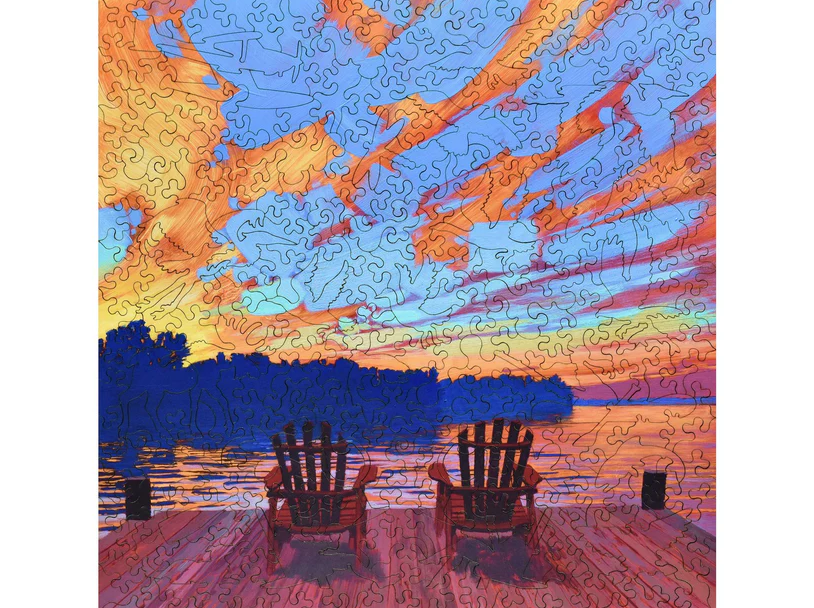 A colorful jigsaw puzzle featuring two red chairs on a wooden dock overlooking a tranquil lake at sunset. The sky is filled with vibrant clouds in shades of orange, pink, and blue, reflecting the peaceful ambiance of the scene. Perfect for puzzle enthusiasts and nature lovers.